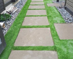 Stone walkway through artificial turf yard